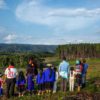 Misak women, men and children observe the contrast between the monoculture pine and eucalyptus plantation, on the right, and the natural forest in their territory, on the left, from a distance.