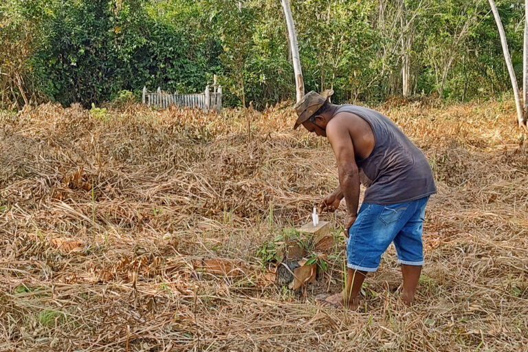 A Quilombolas man lights candles in the cemetery.