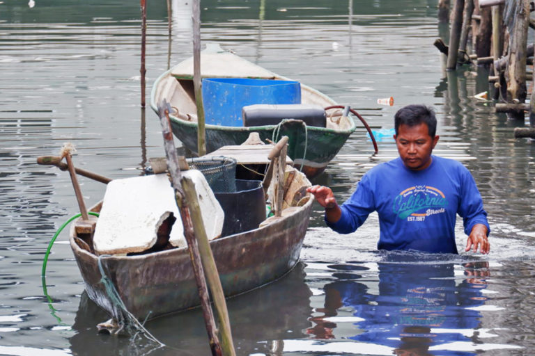 A local fisherman pushing his canoe in the polluted waters.