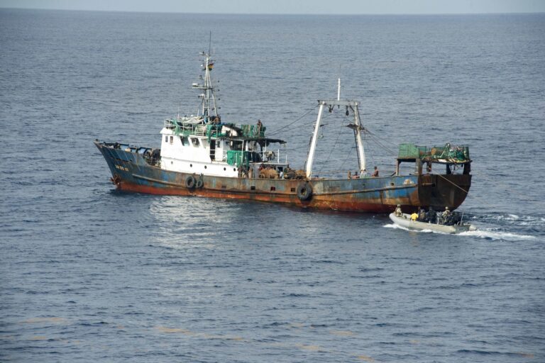 A 50m fishing trawler off the coast of Ghana, patches of rust on its blue hull, a small grey inflatable with US and Ghanaian marines coming up astern. Image by Jeff Atherton/US Navy via Flickr (CC BY-ND 2.0)