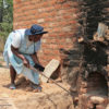 Netty Joyce Mukanganise tends her tobacco-curing barn. Image by Tonderayi Mukeredzi for Mongabay.