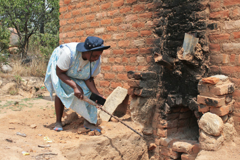 Netty Joyce Mukanganise tends her tobacco-curing barn. Image by Tonderayi Mukeredzi for Mongabay.