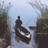 Lone figure in dugout canoe emerging from reeds on river. Image by Patrik M. Loeff via Flickr (CC BY-NC-ND 2.0)