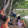 Researcher Elielson Pereira da Silva and Quilombola people sit waiting for a canoe.