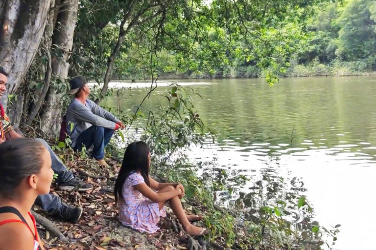 Researcher Elielson Pereira da Silva and Quilombola people sit waiting for a canoe.