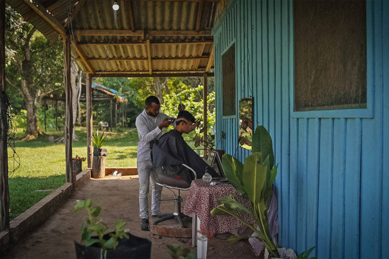 Hairdressser Flávio Mateus do Santo de Sousa cutting the hair of a customer.