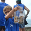 A boy with a jar of cigarette butts.