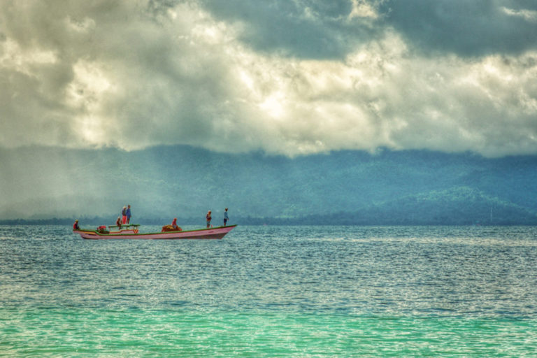 A group of traditional fishermen in small boats catching fish in the waters of Maluku.