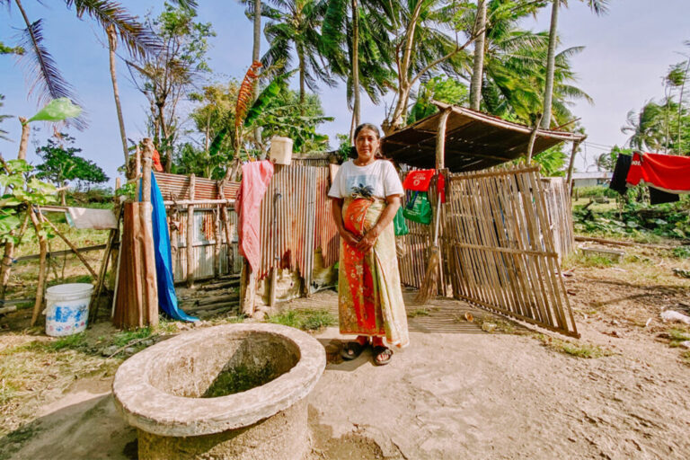 A woman stands next to a well with water that tastes salty due to seawater interference.